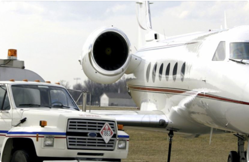 Fuel truck parked next to a business jet on the airport ramp for refueling